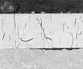 Micrografía de una capa de cromo duro con fisuras verticales que atraviesan el recubrimiento